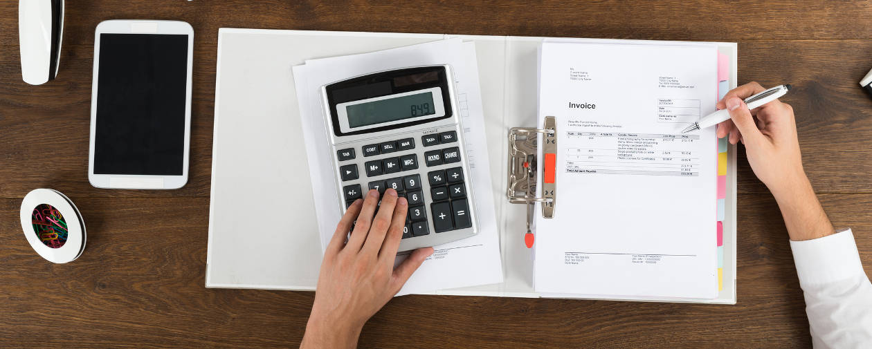 Image of a hand using a calculator and notebook at a desk. Lakeland's BA in Accounting is one of the top 25 online degrees in the US.